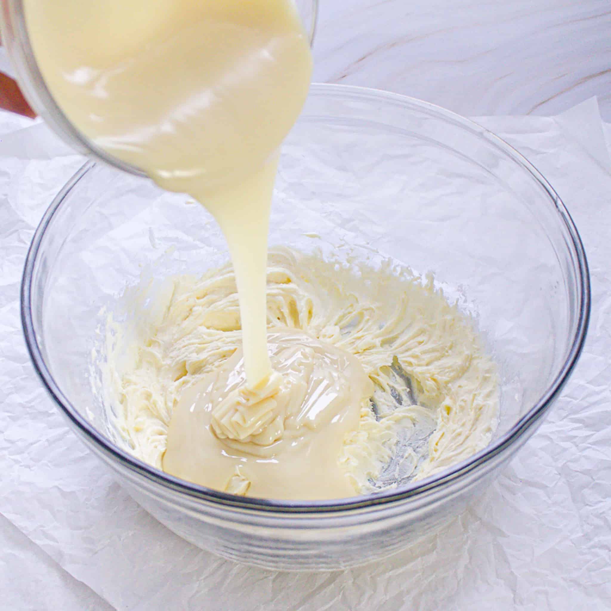 sweetened condensed milk pouring into cream cheese