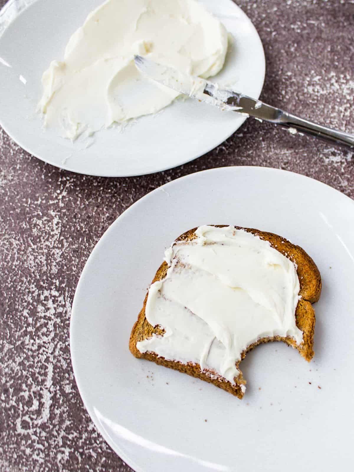 toast with cream cheese spread, bite taken out