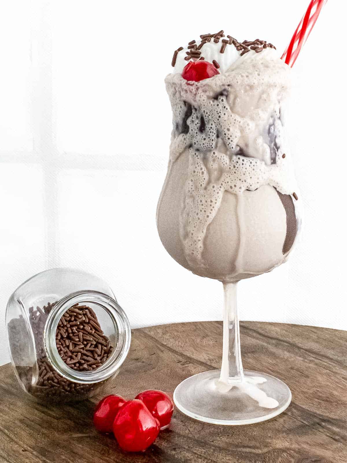 mocktail displayed with jar of sprinkles and three cherries