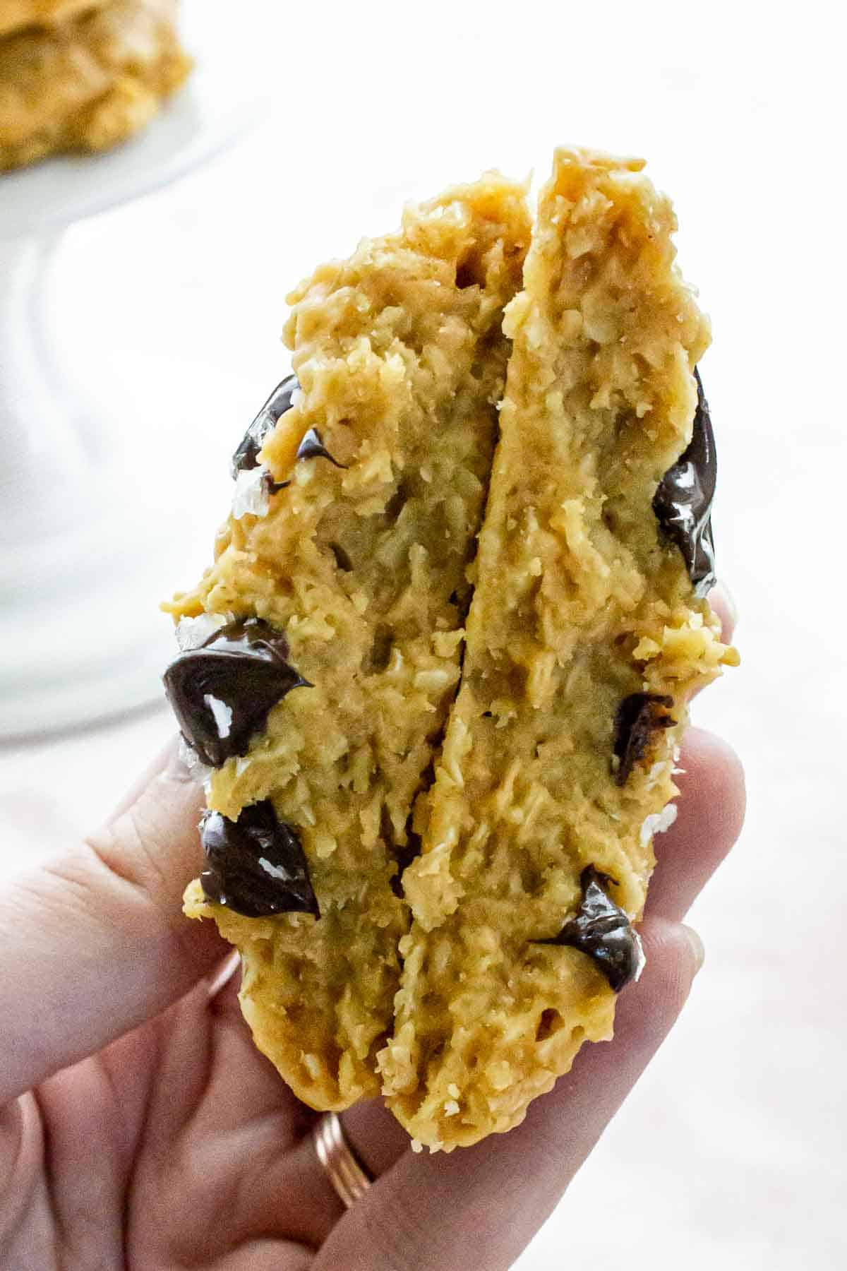 A person holding a partially-eaten no-bake butterscotch cookie.