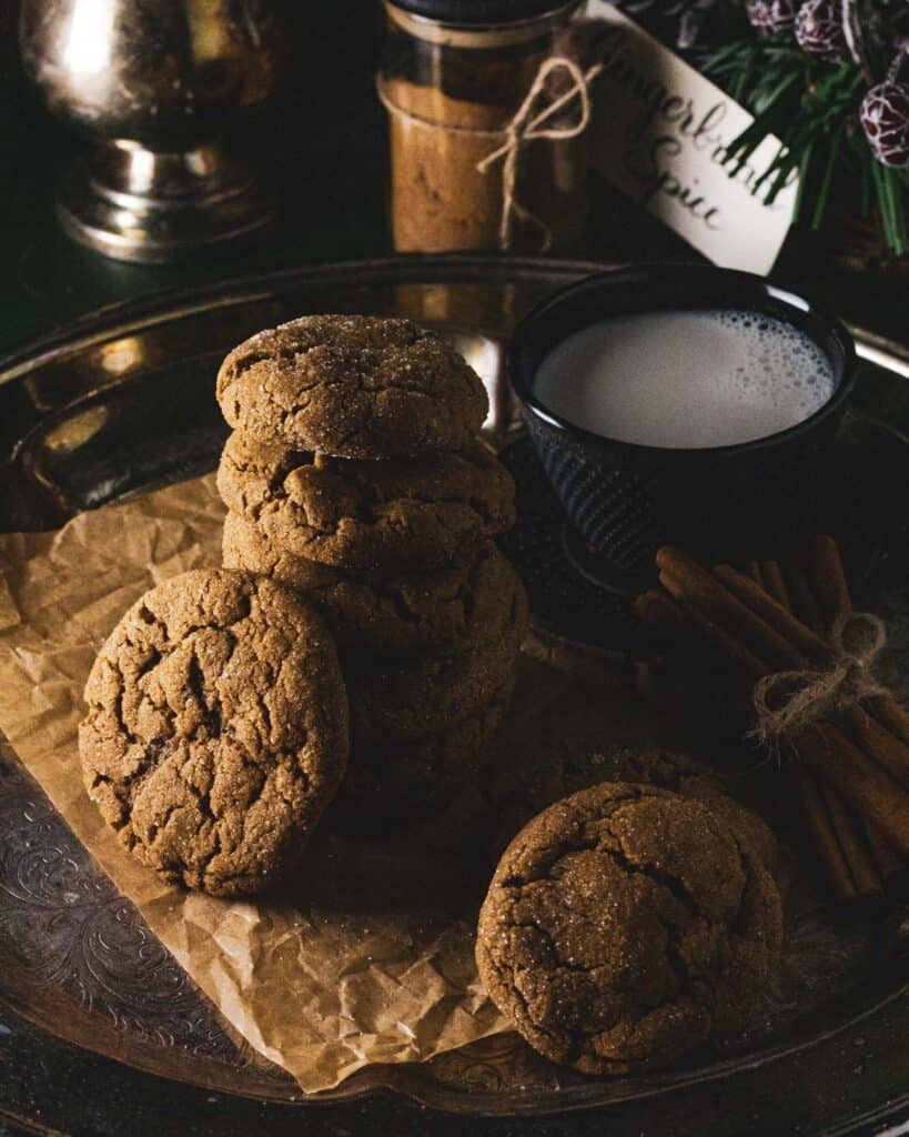 a stack of gingerbread cookies on parchment with a cup of milk