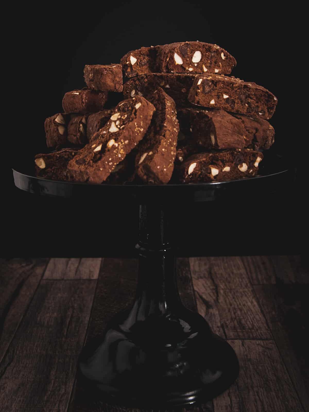 chocolate almond biscotti ontop of a black cake pedestal 