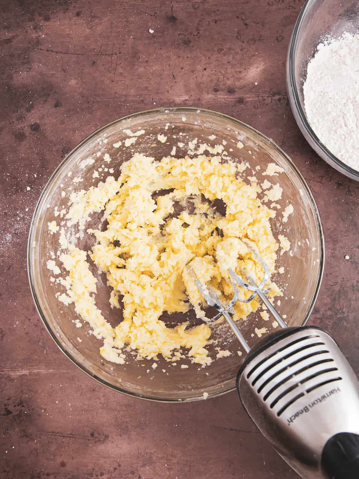 wet ingredients being creamed in a bowl with a hand mixer. 