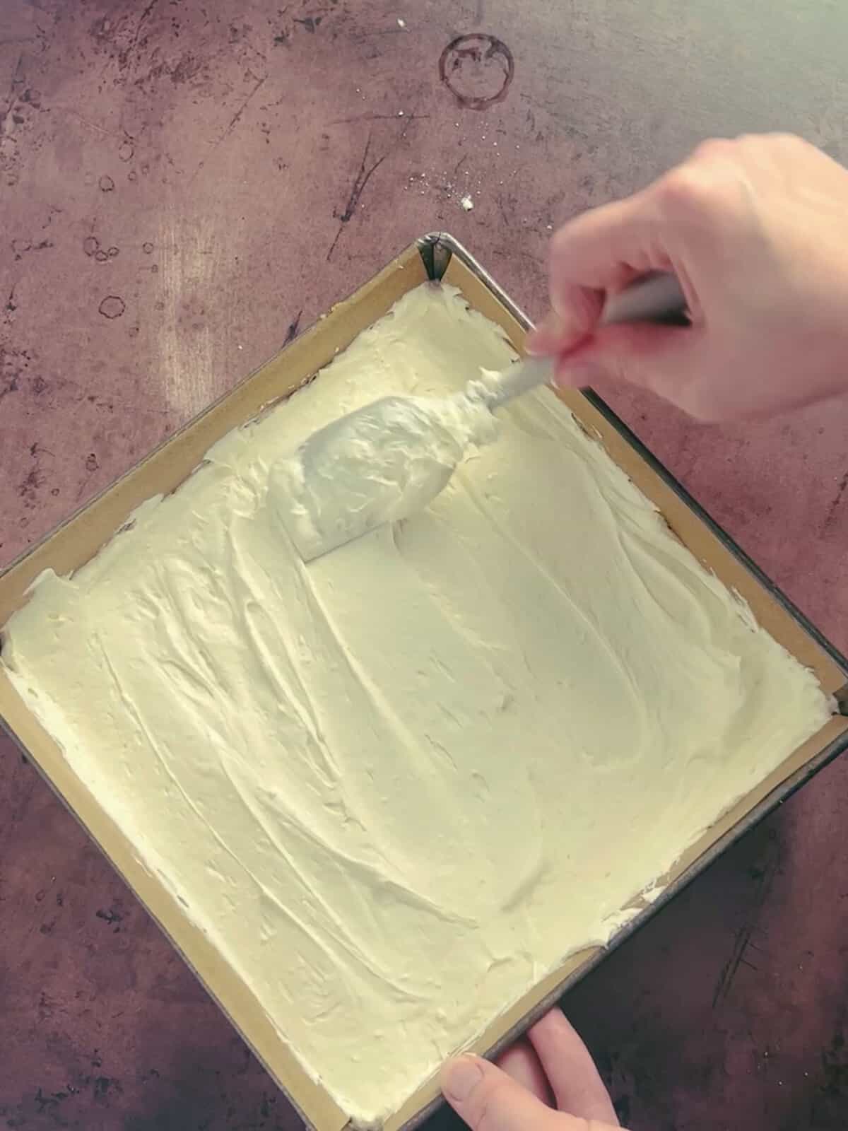 cheesecake filling being spread on top of the cracker crust.