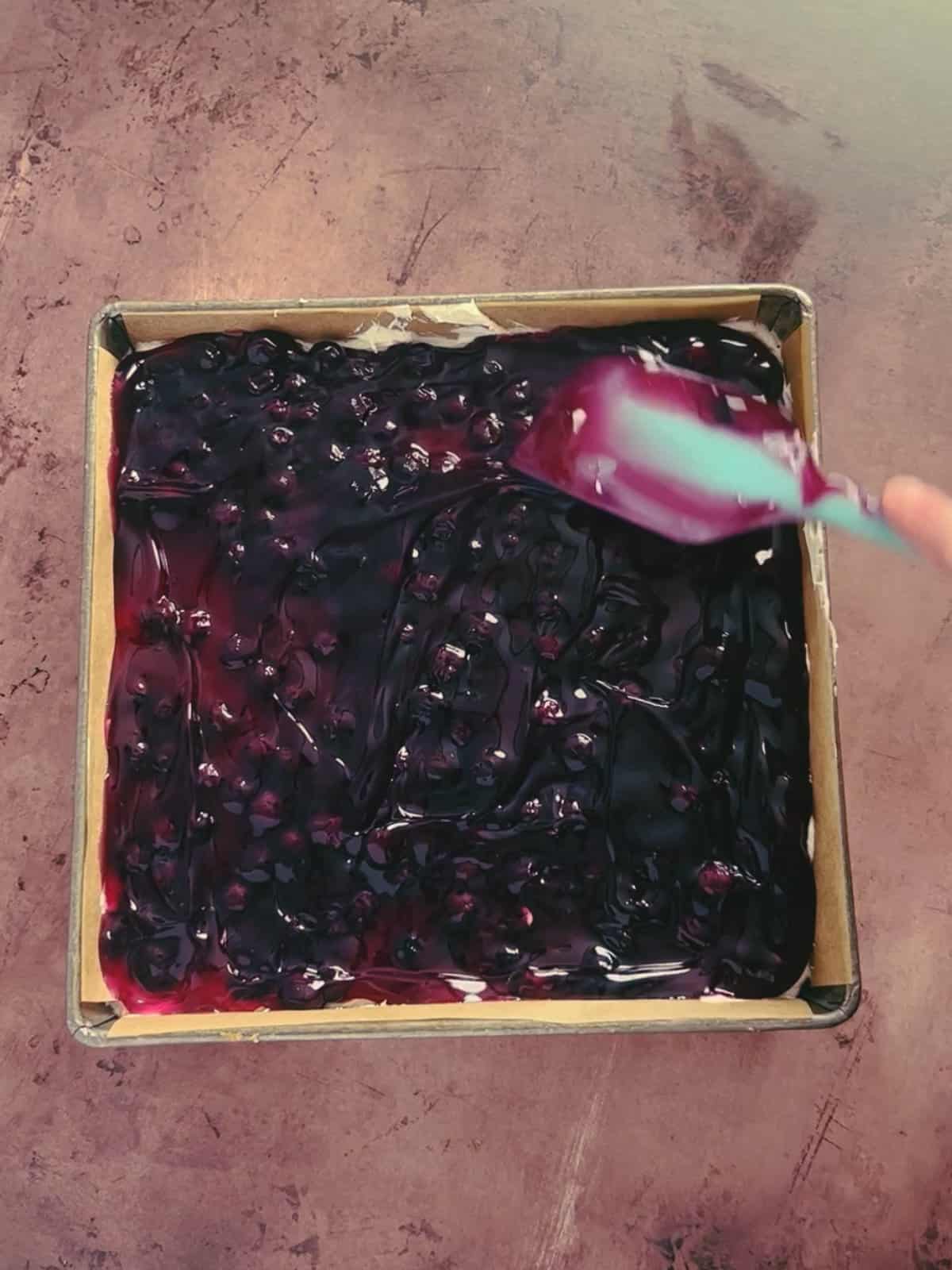 blueberry pie filling being spread across the top.