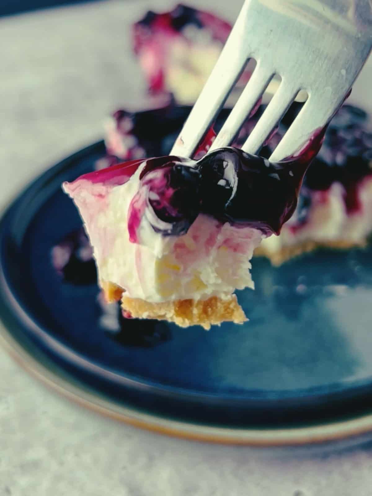 close up of a bite on a fork of blueberry cheesecake.