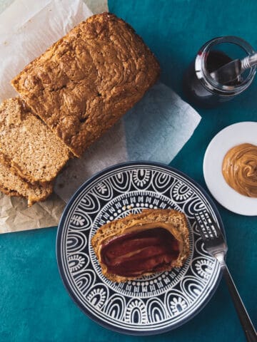 peanut butter bread slice on a plate with peanut butter and jam topping.