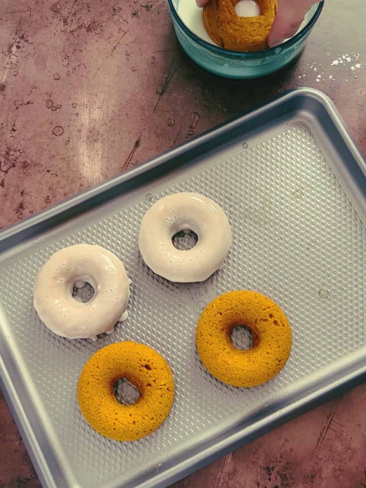 Coating the pumpkin donuts in a vanilla glaze.