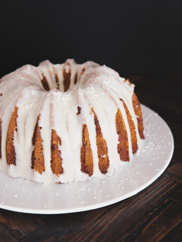 Finished white chocolate bundt cake on a serving tray topped with white chocolate.