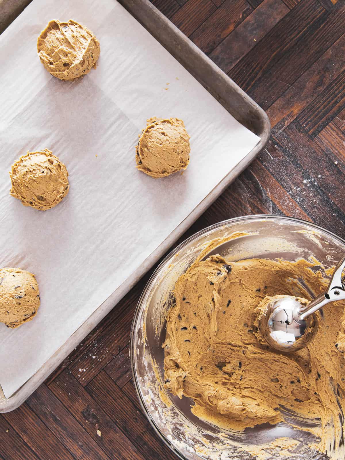 Scooping cookie dough balls onto a baking sheet.