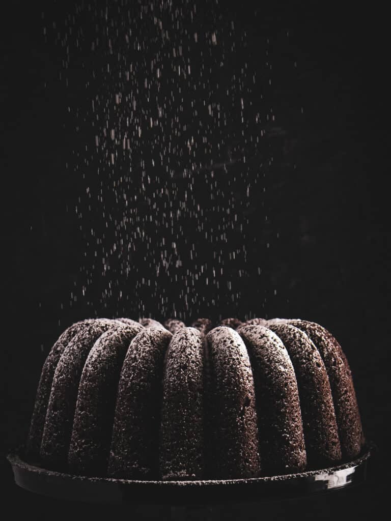 Oreo pound cake being dusted with powdered sugar.