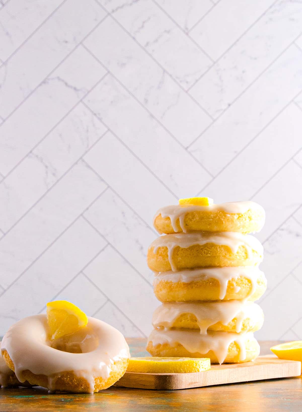 A stack of baked lemon donuts topped with lemon glaze.