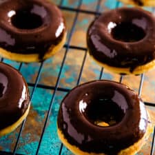 Chocolate covered chocolate chip donuts on a cooling rack.