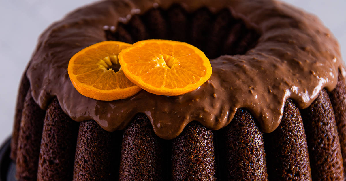 Chocolate orange bundt cake on a cake stand topped with orange slices.