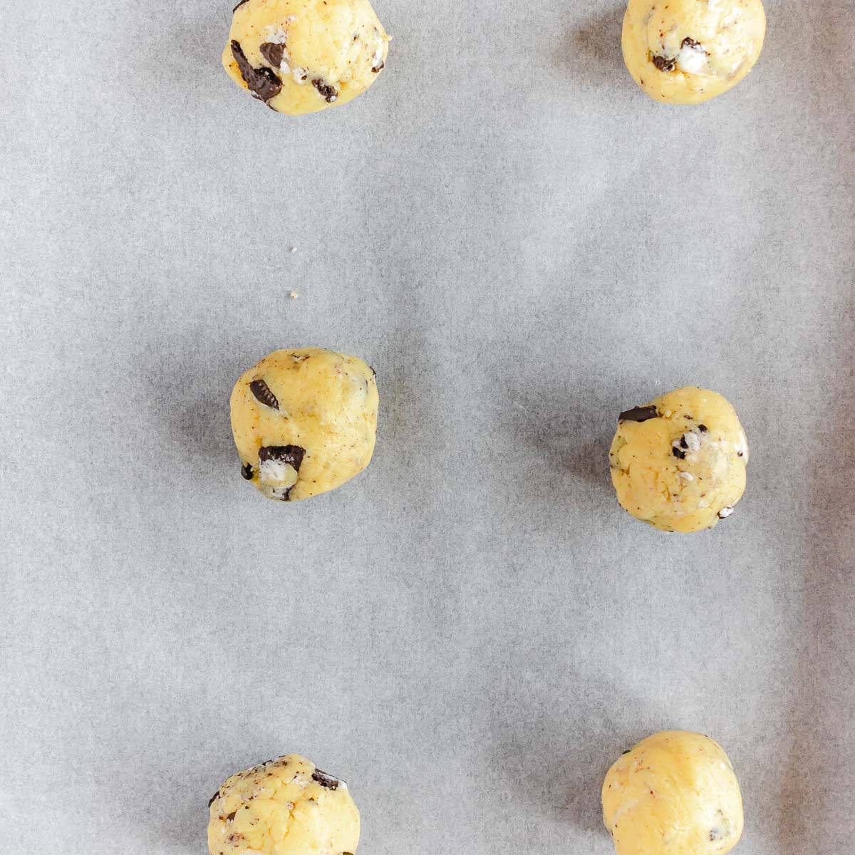 Cookies and cream cookie dough balls on a baking sheet.