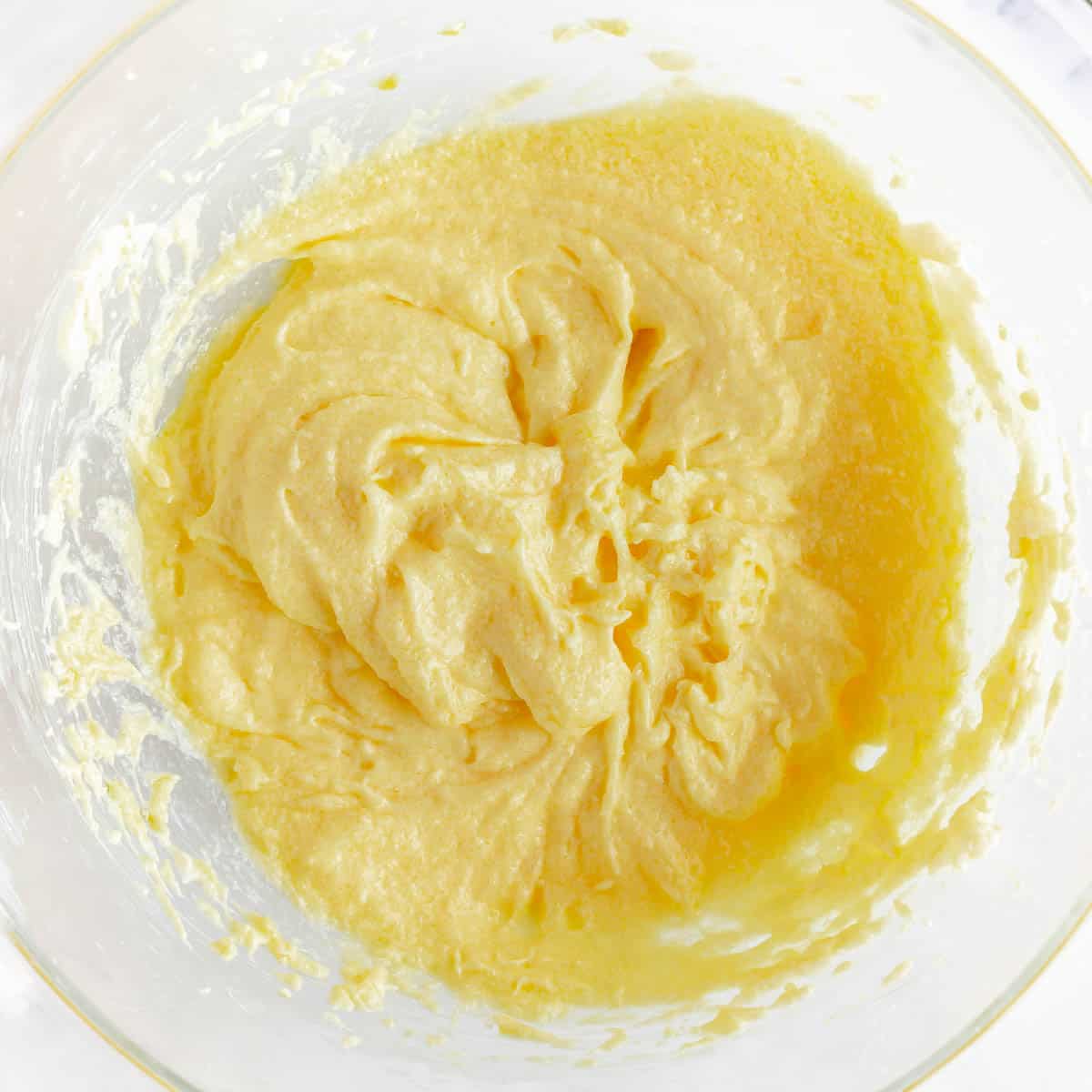A bowl of yellow batter in a mixing bowl.