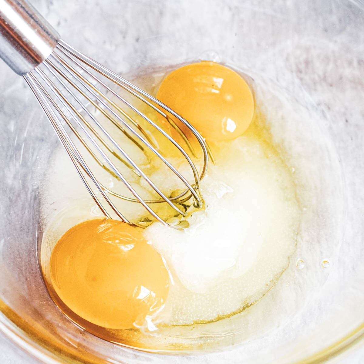 Two eggs in a bowl with a whisk.
